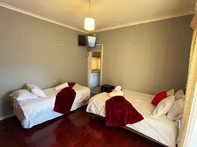 a room with two beds with red blankets on them at M&D Guest House in Bellville