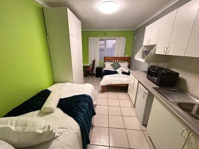 a room with two beds and a kitchen with green walls at M&D Guest House in Bellville