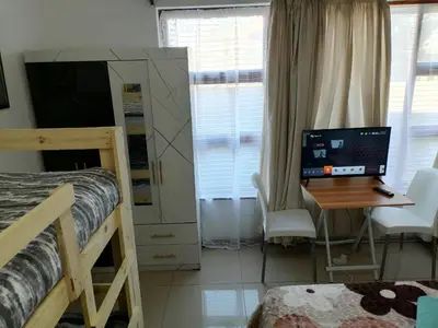 a bedroom with a bed and a desk with a computer at 72 Hamilton the trout lodge in Goodwood