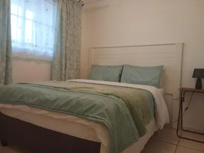 a bedroom with a bed with green sheets and a window at Klipkop Self-catering Haven in Cravenby