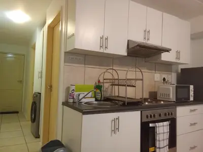 a kitchen with white cabinets and a stove top oven at Klipkop Self-catering Haven in Cravenby