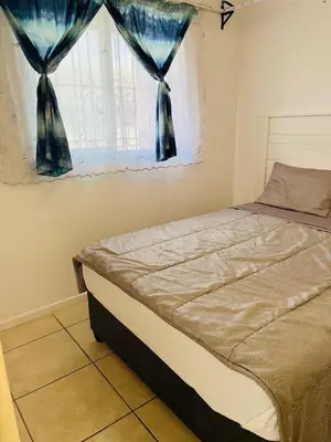 a bedroom with a bed and a window with blue curtains at Klipkop Self-catering Haven in Cravenby
