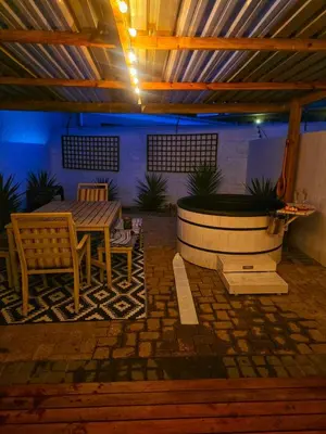a patio with a table and a bench and a fountain at Spring Tide Beach Flat Child Petfriendly Hot Tub in Bloubergstrand