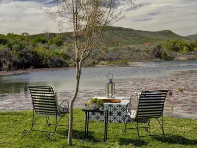 two chairs and a table in front of a lake at Lily Pond in Worcester
