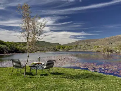 two chairs and a table next to a river at Lily Pond in Worcester