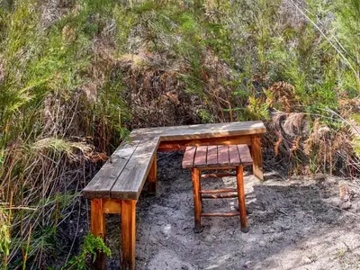 a wooden bench and a chair sitting next to a hill at Vineyard House in Worcester