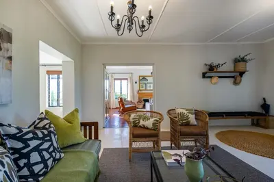 a living room with a green couch and chairs at Libertas House, Cheverells Farm in Grabouw