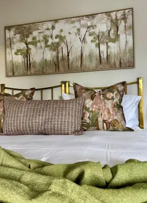 a bed with pillows and a picture on the wall at Libertas House, Cheverells Farm in Grabouw