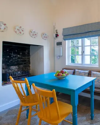 a blue table with chairs and a bowl of fruit on it at Bramley Cottage, Cheverells Farm in Grabouw