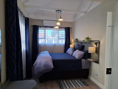 a bedroom with a bed with a blue comforter and a window at Mukuru Okunene in Strand