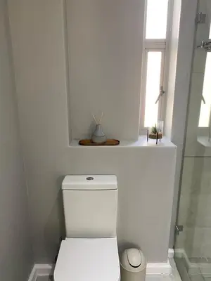 a white bathroom with a toilet and a window at The Madge Self Catering in Paarl