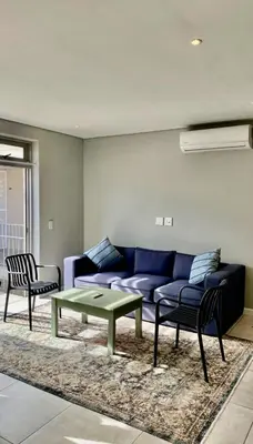 a living room with a blue couch and a table at The Madge Self Catering in Paarl