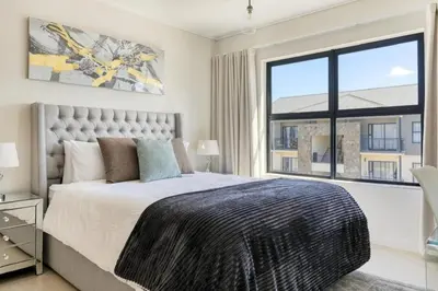 a bedroom with a large bed and a large window at Joseph's Place Sandown CAPE TOWN in Cape Town