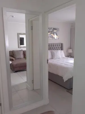 a bedroom with a mirror and a bed and a couch at Joseph's Place Sandown CAPE TOWN in Cape Town