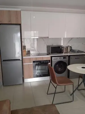 a kitchen with a refrigerator and a table with chairs at Joseph's Place Sandown CAPE TOWN in Cape Town