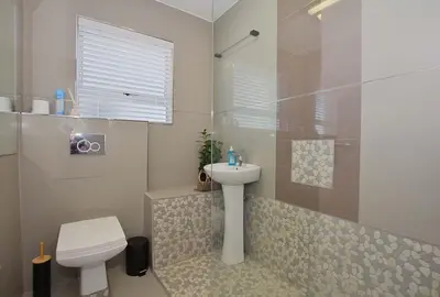 a white bathroom with a sink and a toilet at Ocean View B401 by CTHA in Bloubergstrand