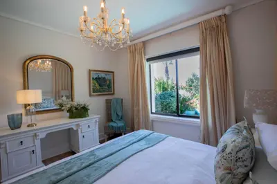a bedroom with a bed and a mirror and a window at Kaniek - Guest Suite in Somerset West