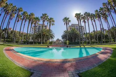 a swimming pool in a park with palm trees at La Savina On Lake 219 The Island Club in Cape Town