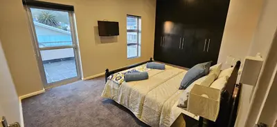 a bedroom with a bed with a television and a window at C-Onrus in Hermanus