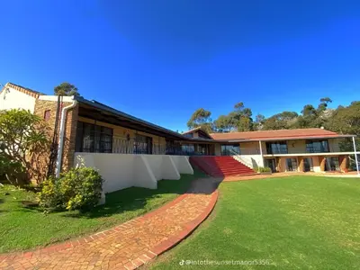 a building with a brick walkway in front of a yard at Into the Sunset Manor in Gordonʼs Bay