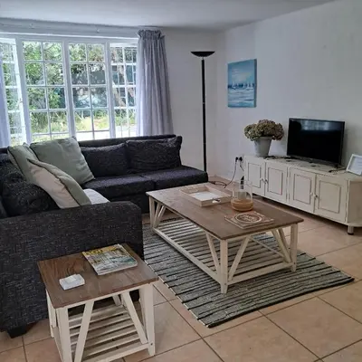 a living room with a couch and a coffee table at Vermont Garden Cottage in Hermanus