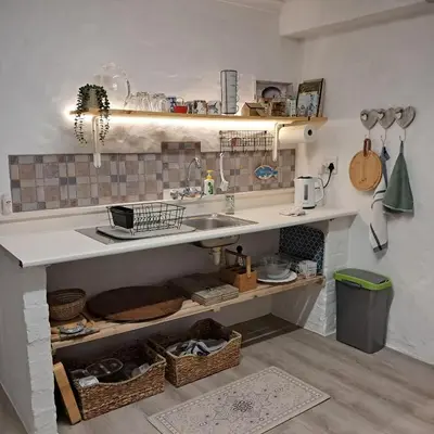 a kitchen with a sink and a counter with baskets at Vermont Garden Cottage in Hermanus