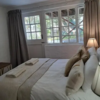 a bedroom with a large white bed with pillows at Vermont Garden Cottage in Hermanus