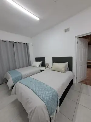 two beds in a white room with at Azzure Apartments 4 sleeper Crawford in Cape Town