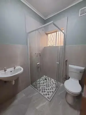 a bathroom with a shower and a toilet and a sink at Azzure Apartments 6 sleeper Crawford in Cape Town