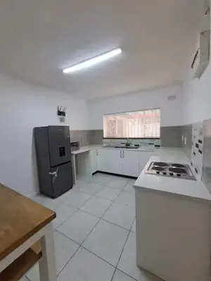 a white kitchen with a stove and a refrigerator at Azzure Apartments 6 sleeper Crawford in Cape Town