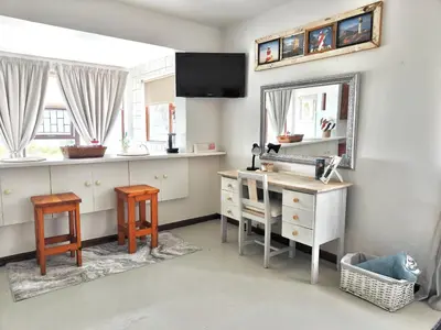a bathroom with a sink and a mirror and a desk at Sand Sittie in Sandbaai