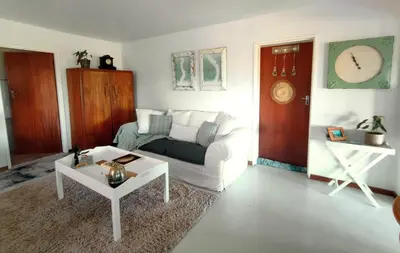 a living room with a white couch and a table at Sand Sittie in Sandbaai