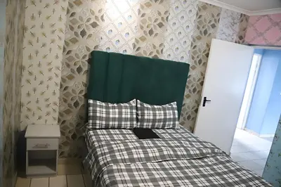 a small bedroom with a bed with a green headboard at Browns villa in Cape Town