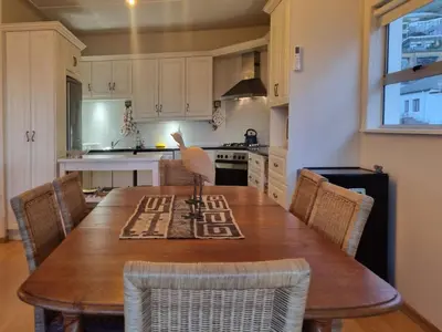 a kitchen with a wooden table and chairs at 'Top Flat' Apartment with Easy Beach Access, Sea front sleeps 5 in Gordonʼs Bay