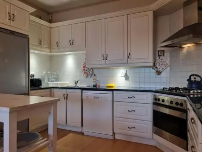 a kitchen with white cabinets and a stove top oven at 'Top Flat' Apartment with Easy Beach Access, Sea front sleeps 5 in Gordonʼs Bay