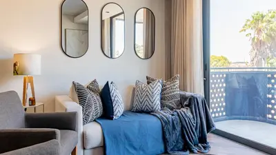 a living room with a couch and mirrors on the wall at Table Mountain View Apartment in Cape Town