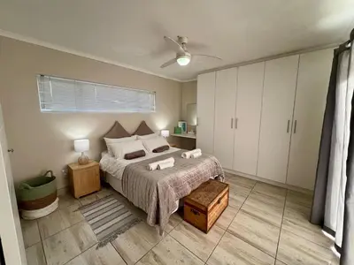 a bedroom with a bed and a ceiling fan at Private Garden Flat Blouberg Beach in Cape Town