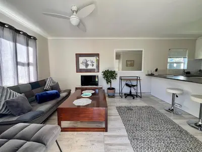 a living room with a couch and a table at Private Garden Flat Blouberg Beach in Cape Town