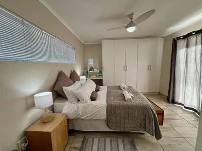 a bedroom with a bed and a ceiling fan at Private Garden Flat Blouberg Beach in Cape Town