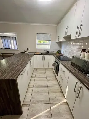 a kitchen with white cabinets and a wooden counter top at Private Garden Flat Blouberg Beach in Cape Town