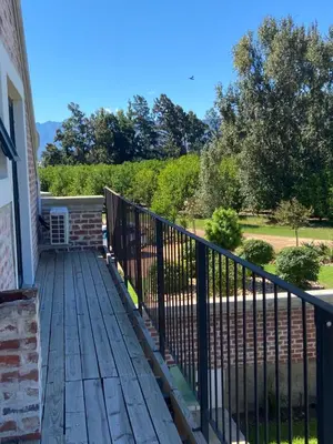 a porch with a black fence and trees at Beertjie Bos in Paarl
