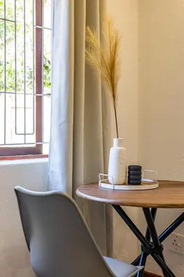 a table with a chair and a vase on it at Bed On Boucher in Durbanville