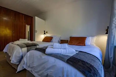 a bedroom with two beds with white sheets at Bed On Boucher in Durbanville