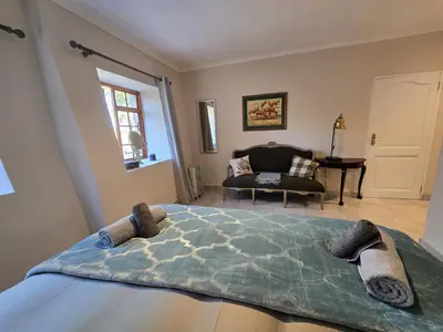 a bedroom with a large bed and a chair at Susans Cottage Peace and Quiet in Villiersdorp