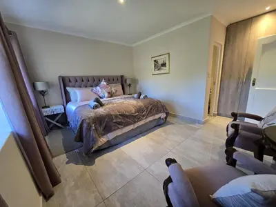 a bedroom with a bed and a chair in it at Susans Cottage Peace and Quiet in Villiersdorp