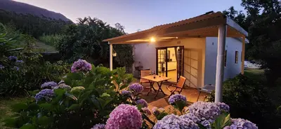 a small house with a table and purple flowers at Sunkiss Cottage on Mount Joy Farm in Stellenbosch