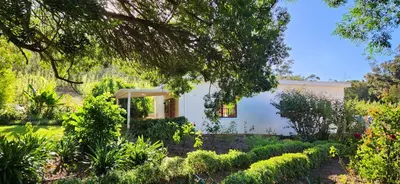 a white house with a garden in front of it at Sunkiss Cottage on Mount Joy Farm in Stellenbosch
