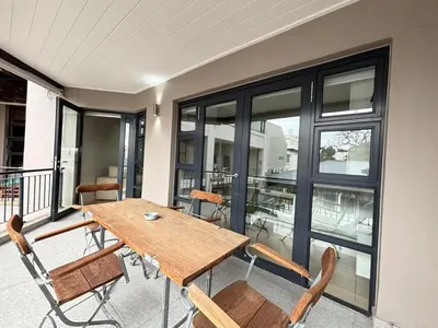 a wooden table and chairs on a balcony at Modern living in central town in Stellenbosch
