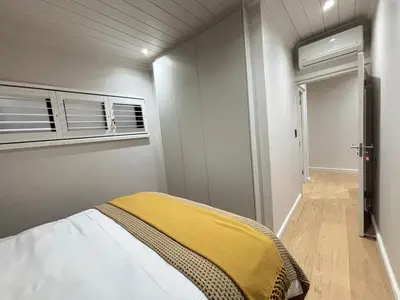 a bedroom with a bed with a yellow blanket on it at Modern living in central town in Stellenbosch