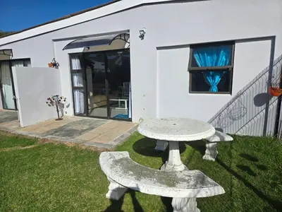 a white house with a table in the yard at Cozy Cottage in Hermanus